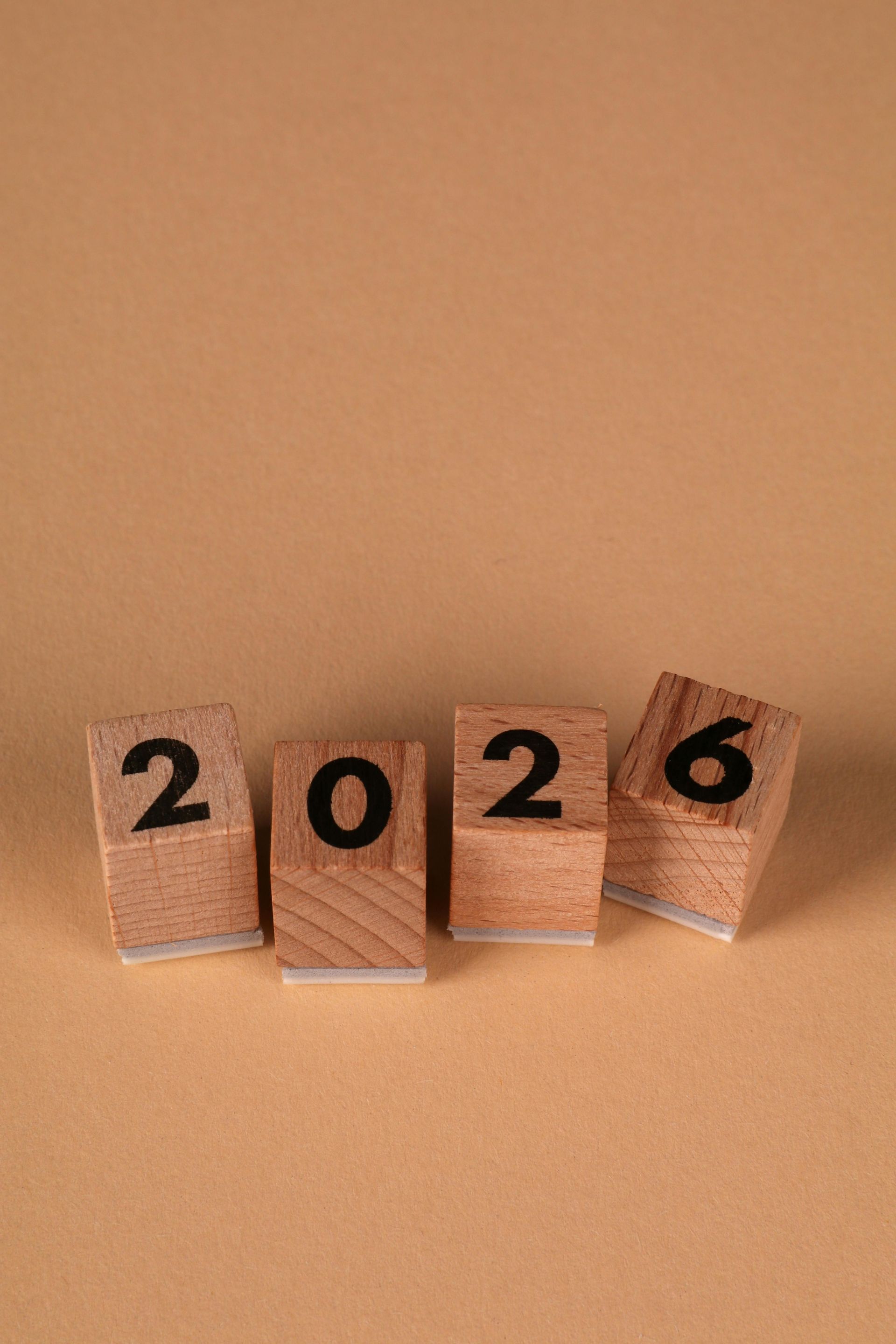 Ξύλινα τουβλάκια που γράφουν «2026» σε καφέ επιφάνεια.