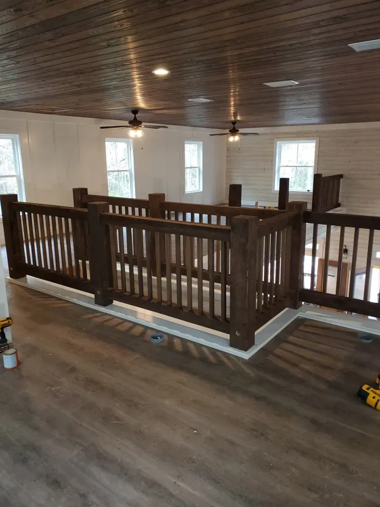 A room with a wooden railing and a ceiling fan.