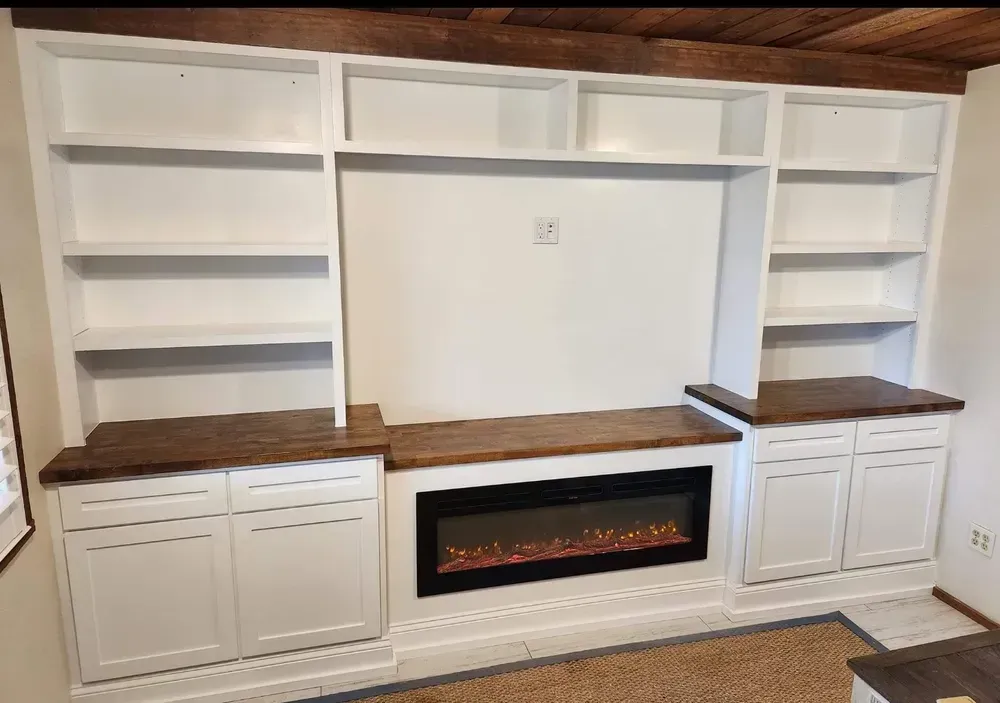 A living room with a fireplace , shelves , and cabinets.