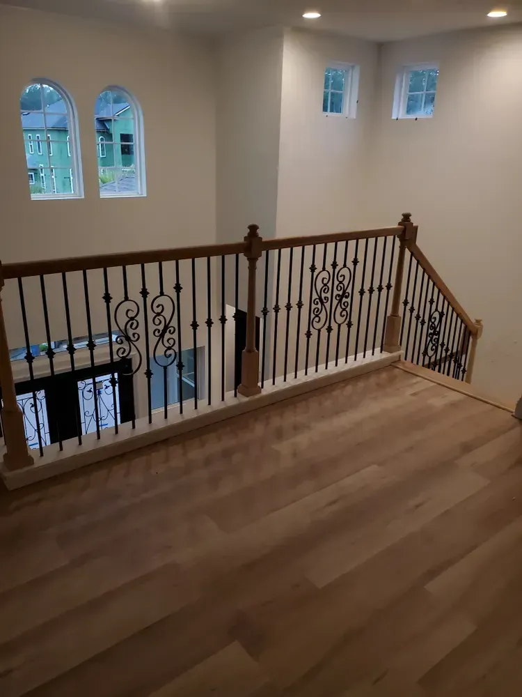 A staircase with a wooden railing and a wrought iron railing