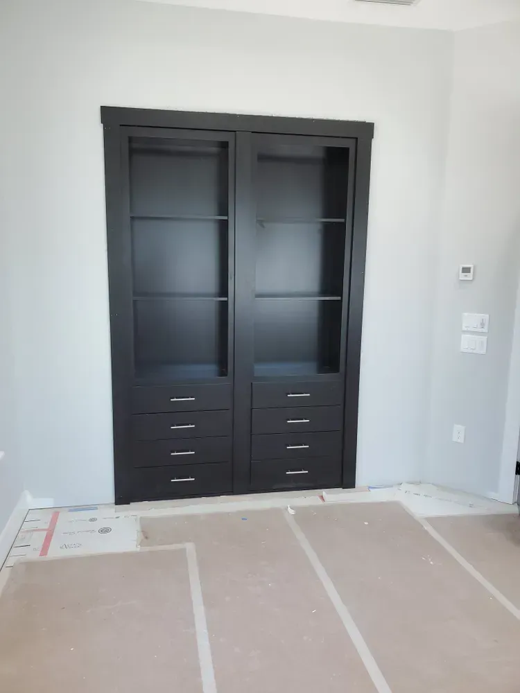 A room with a bookcase and drawers in it