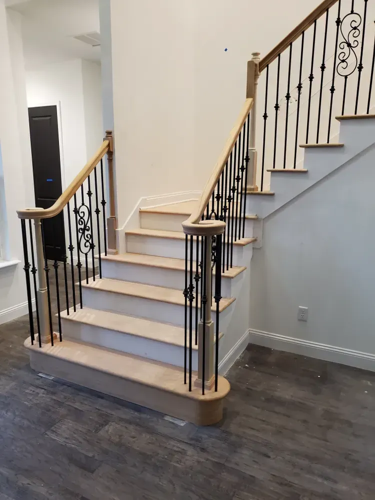 A wooden staircase with a wrought iron railing