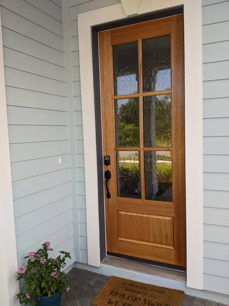 The front door of a house has a welcome mat on the porch