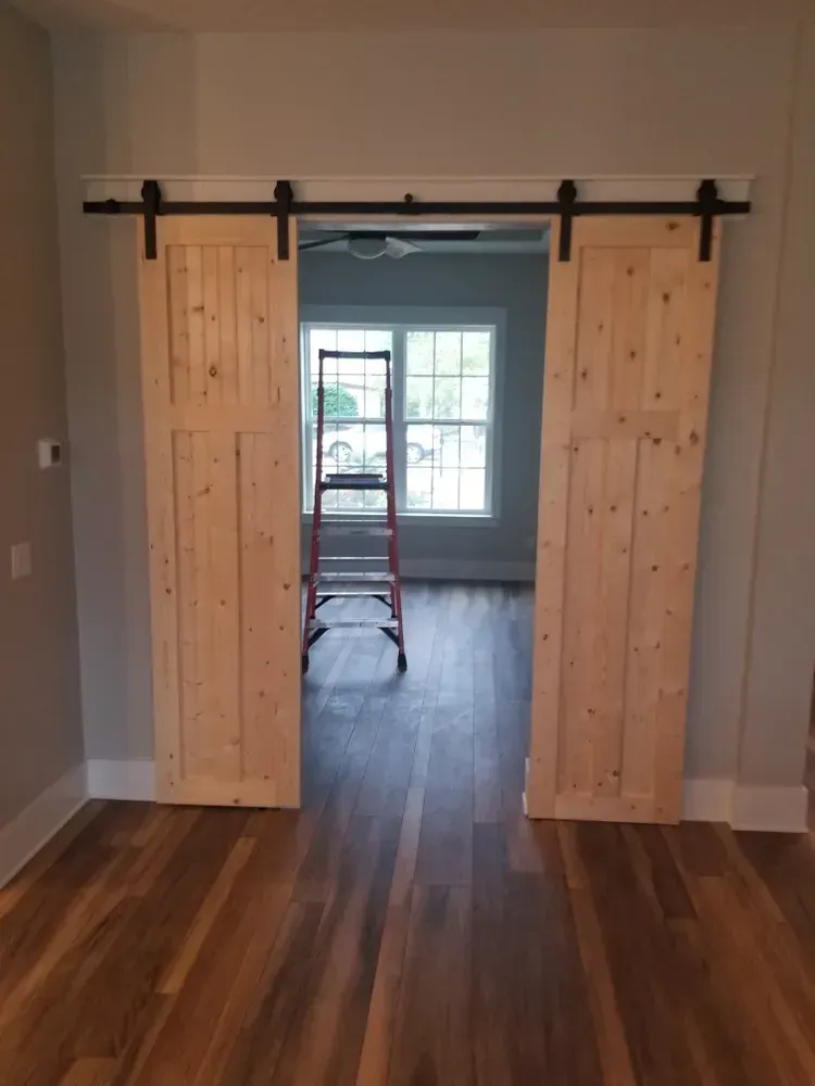 A room with sliding barn doors and a ladder in it.