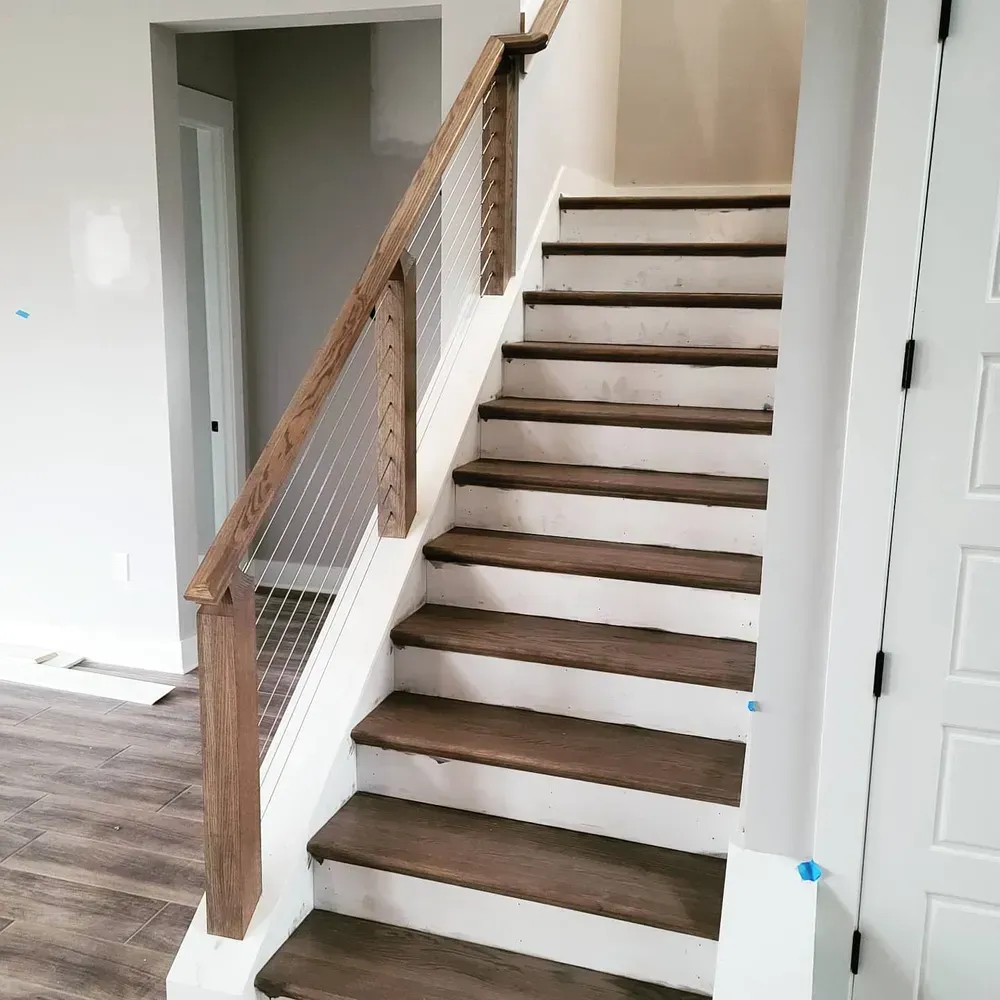 A white staircase with wooden steps and a wooden railing in a house.