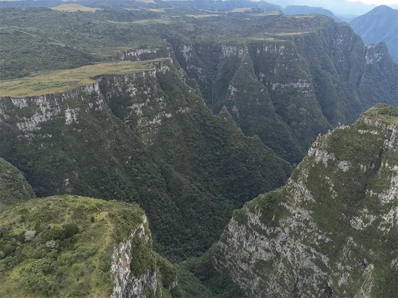 Paisagem verde e rochosa de cânion com floresta densa e penhascos íngremes.