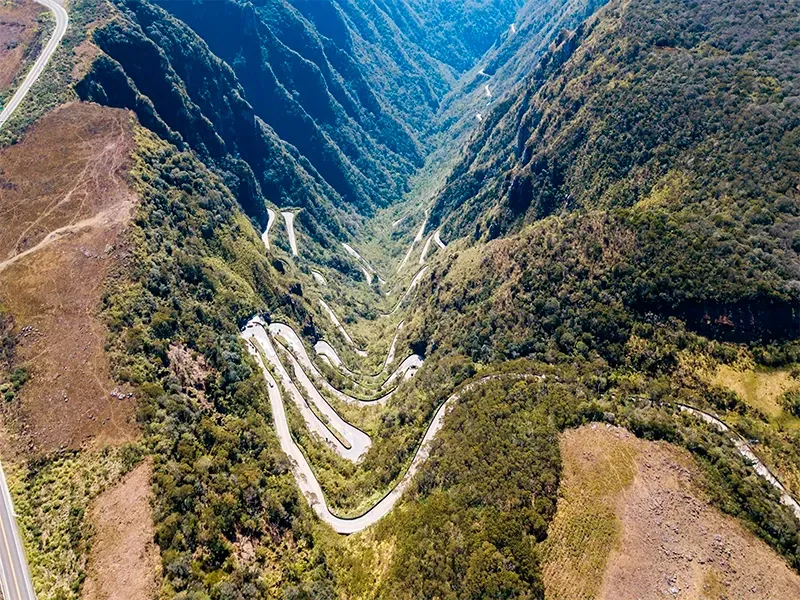Estrada sinuosa que atravessa um vale montanhoso profundo e verdejante.