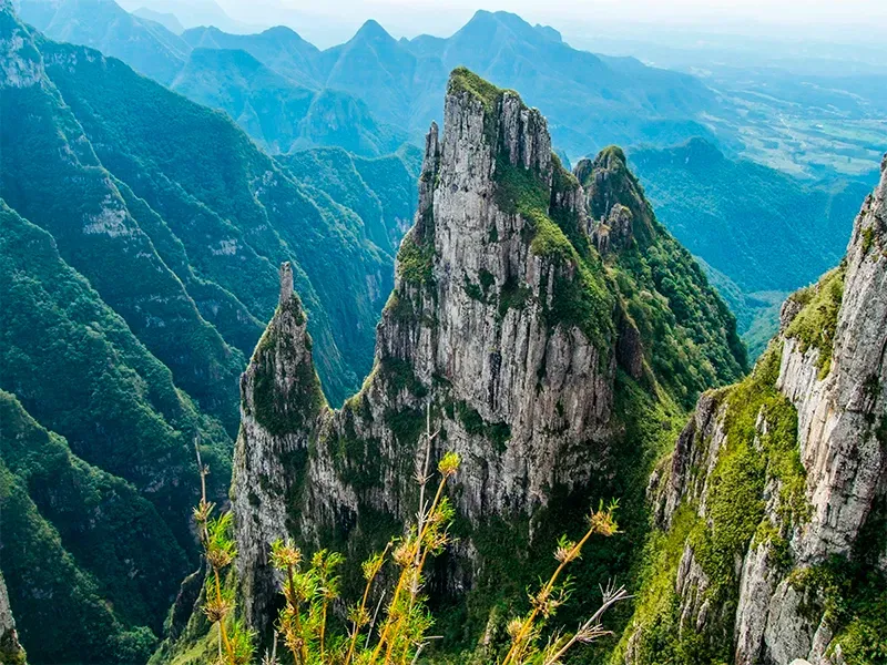 Picos montanhosos irregulares e cobertos de vegetação elevam-se acima de um vale.