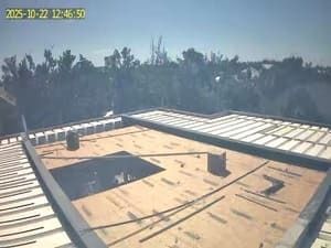 Rooftop under construction with metal panels, roof openings, and a timestamp in the corner.