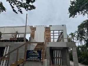 Modern building under construction with a staircase, wooden scaffolding, and a sign at the entrance