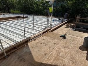 Construction site with plywood decking and rebar framing on a partially built floor