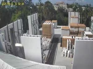 Construction site with stacked white panels, lumber, and pallets under bright daylight.