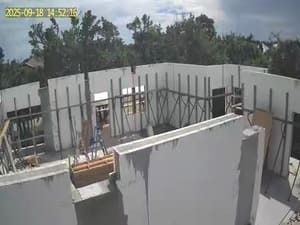 Partially built concrete structure with scaffolding and rebar under a cloudy sky