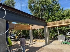 Construction site with workers inspecting a steel beam framework under a blue sky