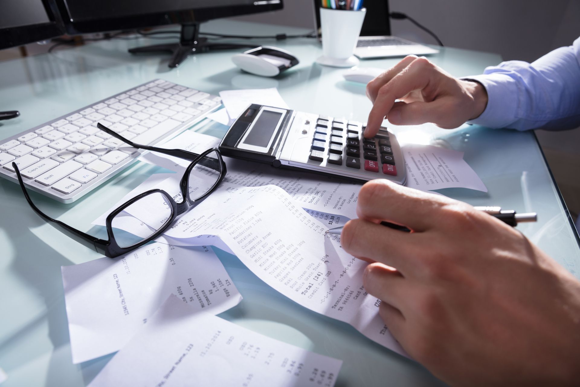 A person is sitting at a desk using a calculator.