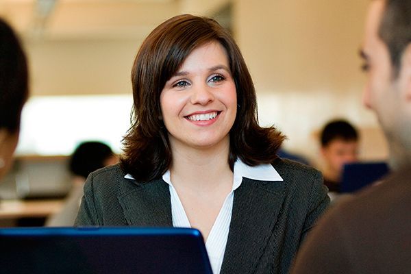 a woman is smiling while sitting at a table with a laptop .