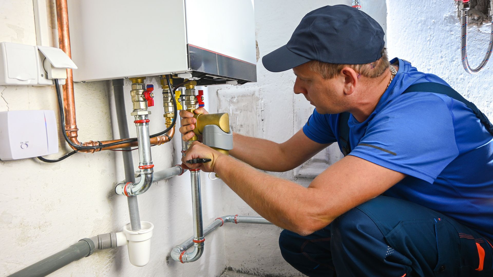A commercial heating contractor is working on a boiler, installing connection pipes for a system. A commercial heating contractor is working on a boiler, installing connection pipes for a system.