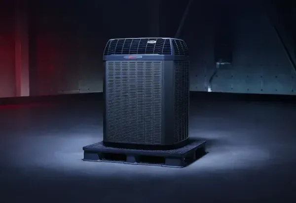Air conditioning unit on a pallet, under a dark, dramatic light in an industrial setting.