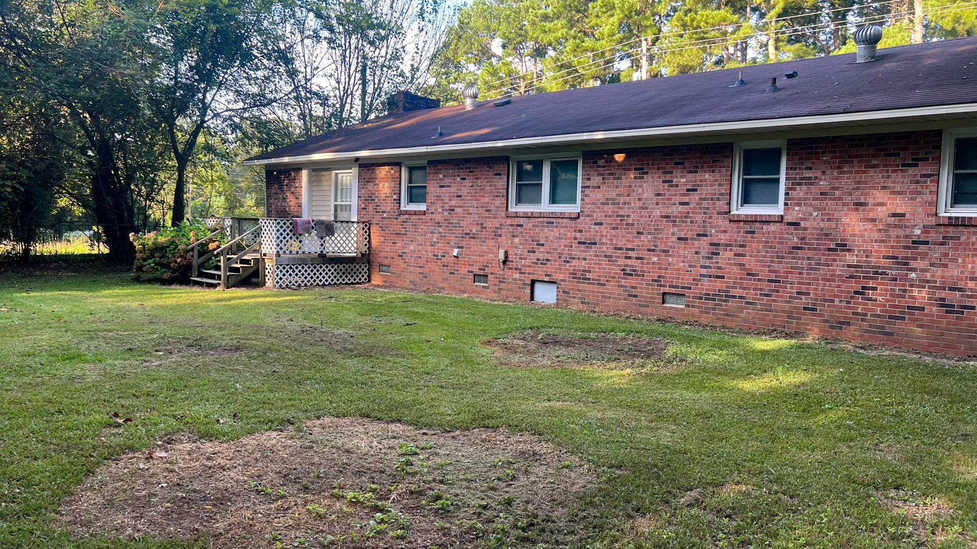 A brick house with a large lawn in front of it.