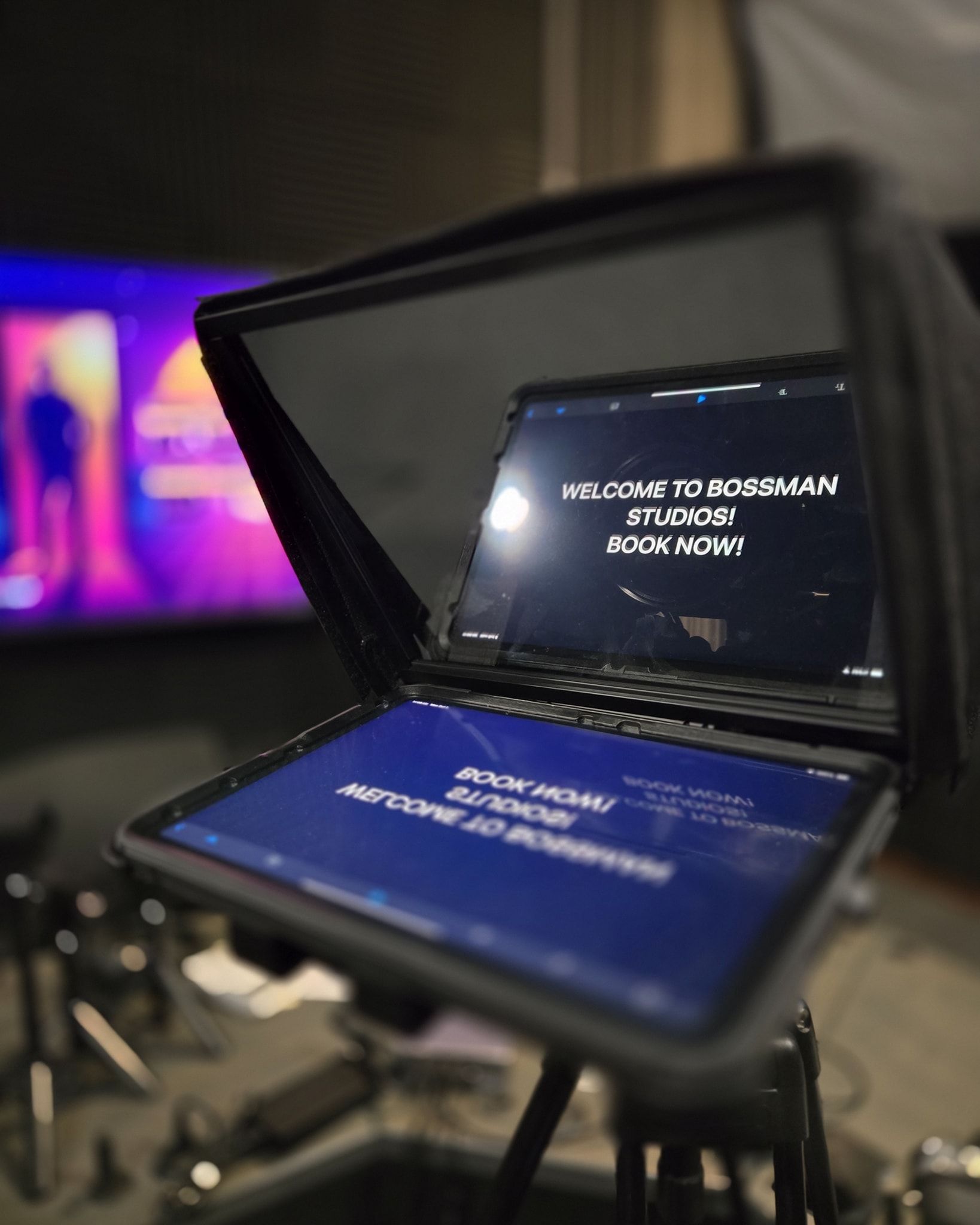 Teleprompter setup with dual screens showing white text on a blue background in a studio