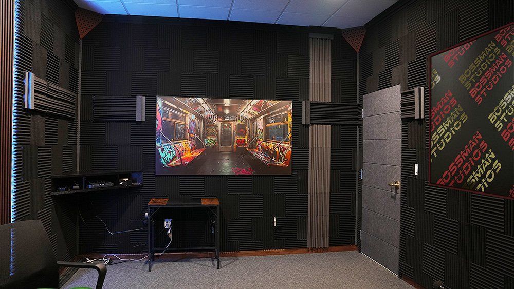 Soundproofed studio with a wall-mounted TV showing a colorful city scene and desk setup
