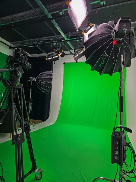 Green screen studio with lighting equipment and camera gear on a cyc wall