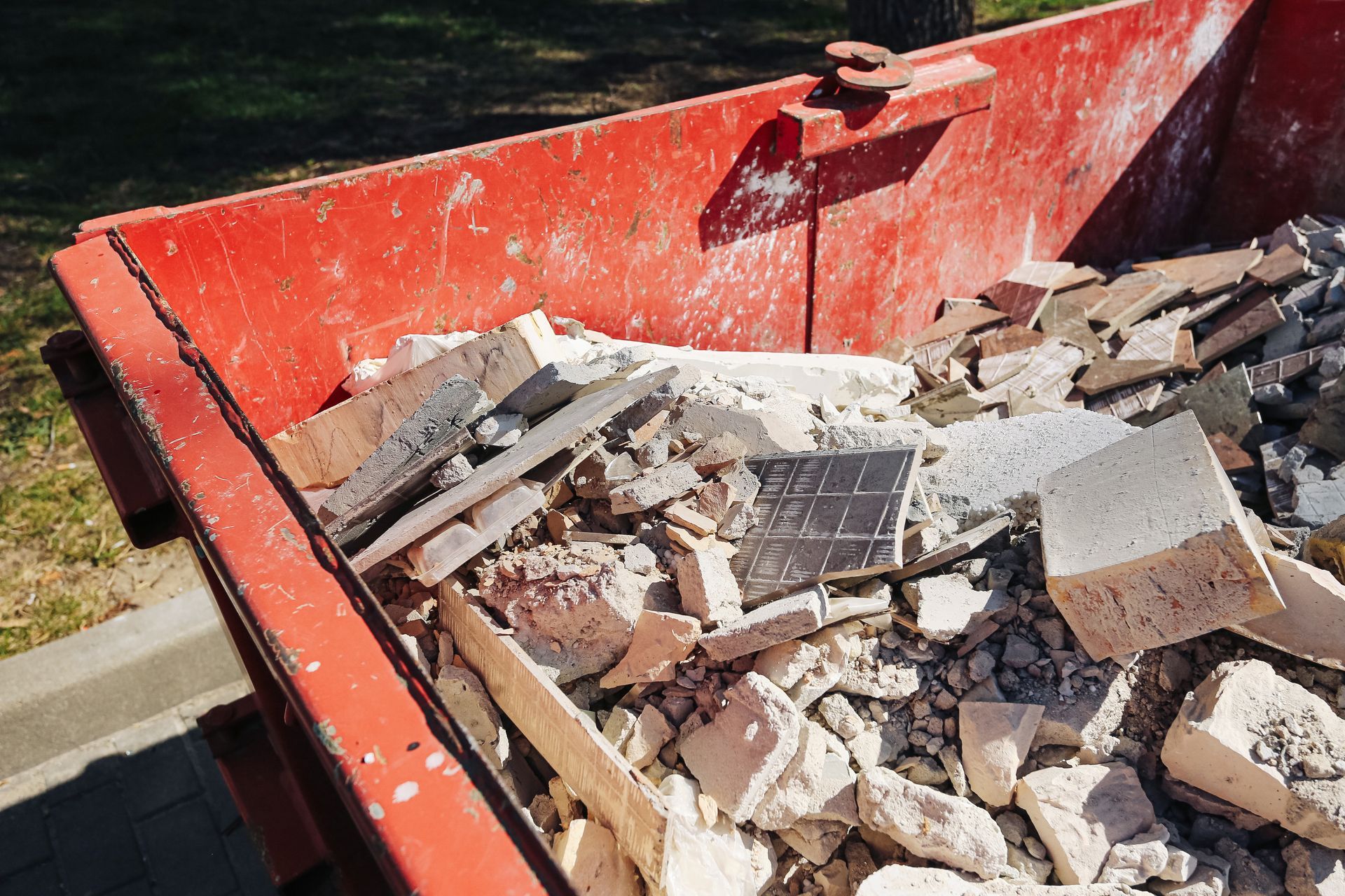 Red dumpster filled with construction debris and broken concrete outdoors Red dumpster filled with construction debris and broken concrete outdoors