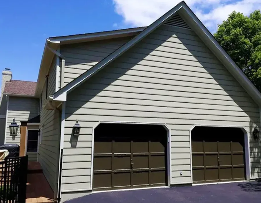 Two-car garage with beige siding and dark brown doors on a sunny day