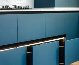 Blue kitchen cabinets with a sleek countertop and under-cabinet lighting.
