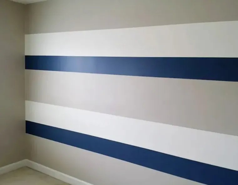 Empty room corner with beige walls and two dark blue horizontal stripes on white bands.