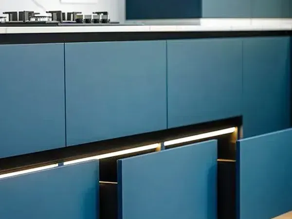 Blue kitchen cabinets with a black countertop and under-cabinet lighting.