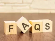 Wooden blocks spelling FAQS on a tabletop against a blurred brick background