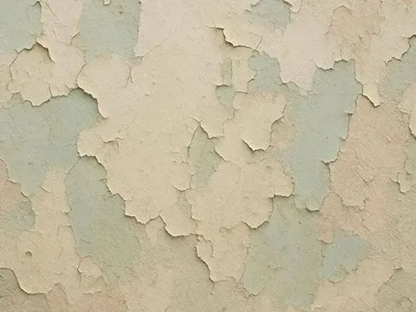 Peeling beige and pale green wall paint with a cracked, weathered texture