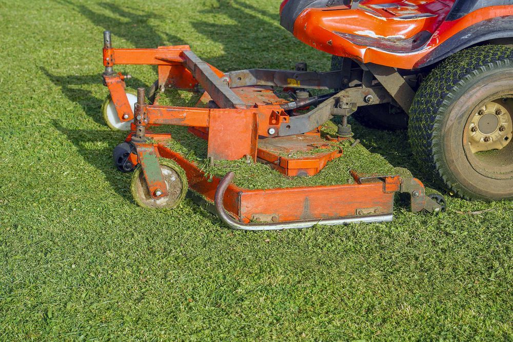 A Tractor With an Orange, Articulated Mower Arm Extending Into Roadside Grass — Old Mates Grass Cutters in Deeragun, QLD