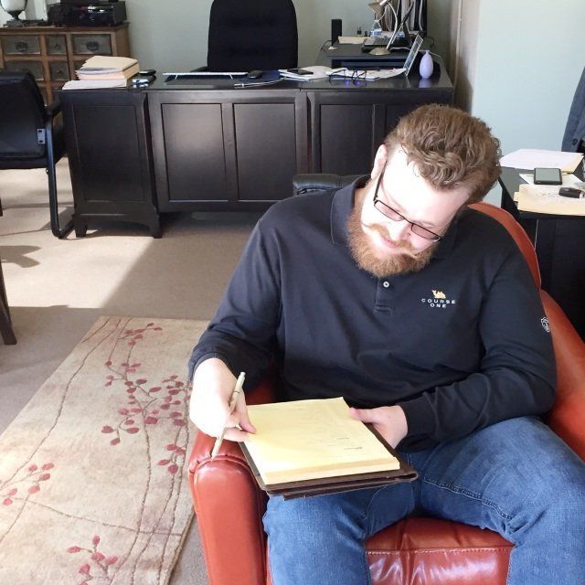 A man is sitting in a chair writing in a notebook