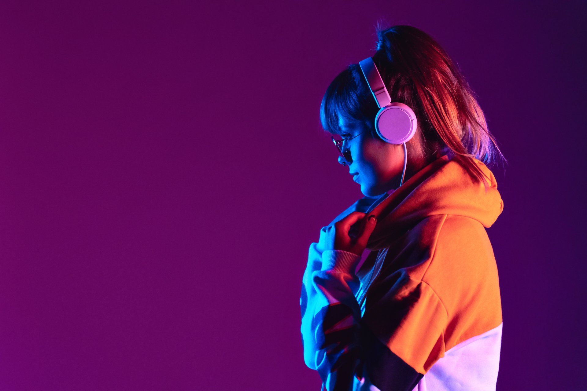 A woman wearing headphones is listening to music on her phone.