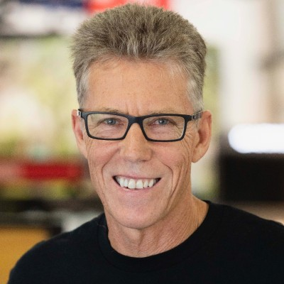 Smiling man with glasses in a black shirt.