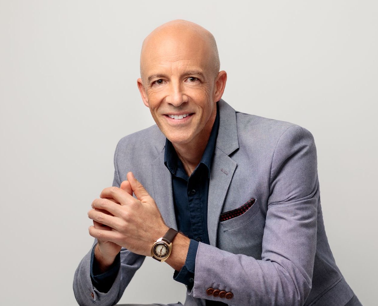 Michael Ceely, executive coach, in a grey blazer and blue shirt smiling.