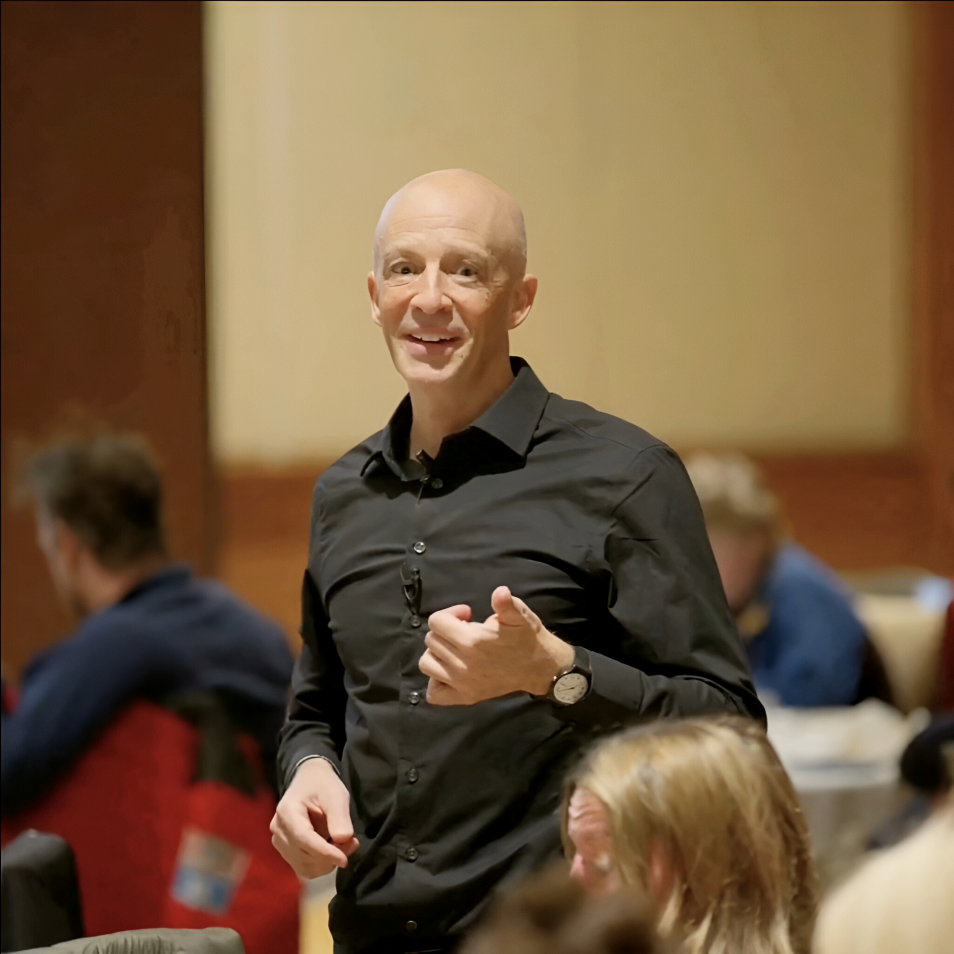 Michael Ceely in a black shirt speaking to an audience in a conference room.