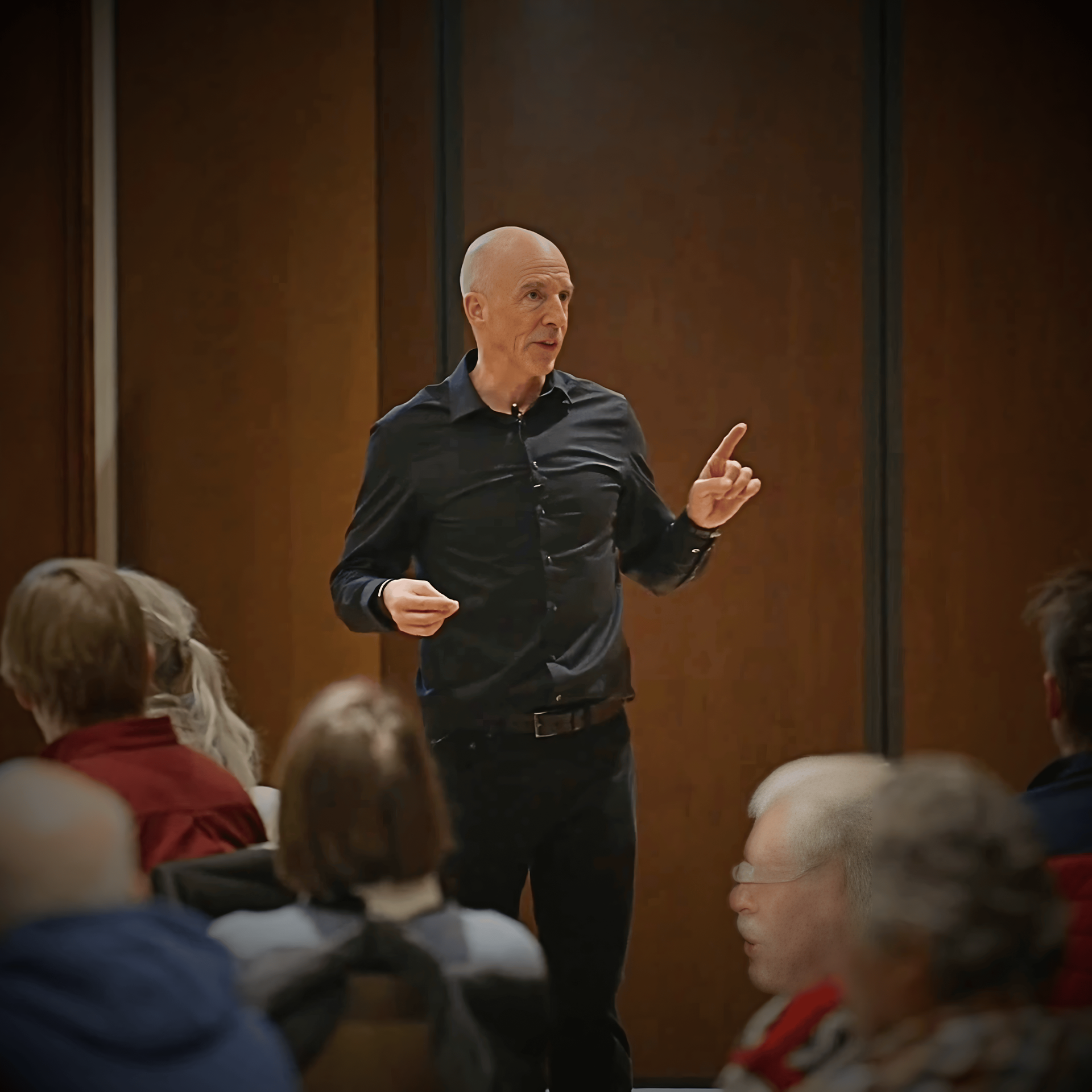 Michael Ceely presenting to an audience, gesturing with one hand while standing.