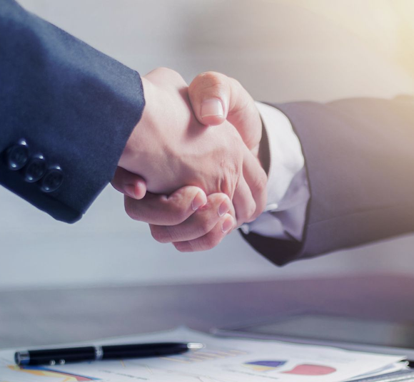 Business handshake over documents with pen on desk