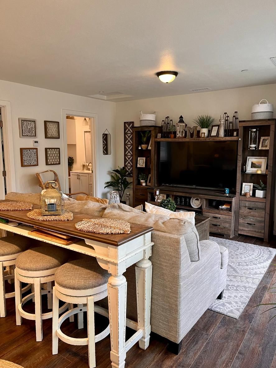Cozy living room with a wooden TV wall unit, sofa, rug, and open kitchen island with stools