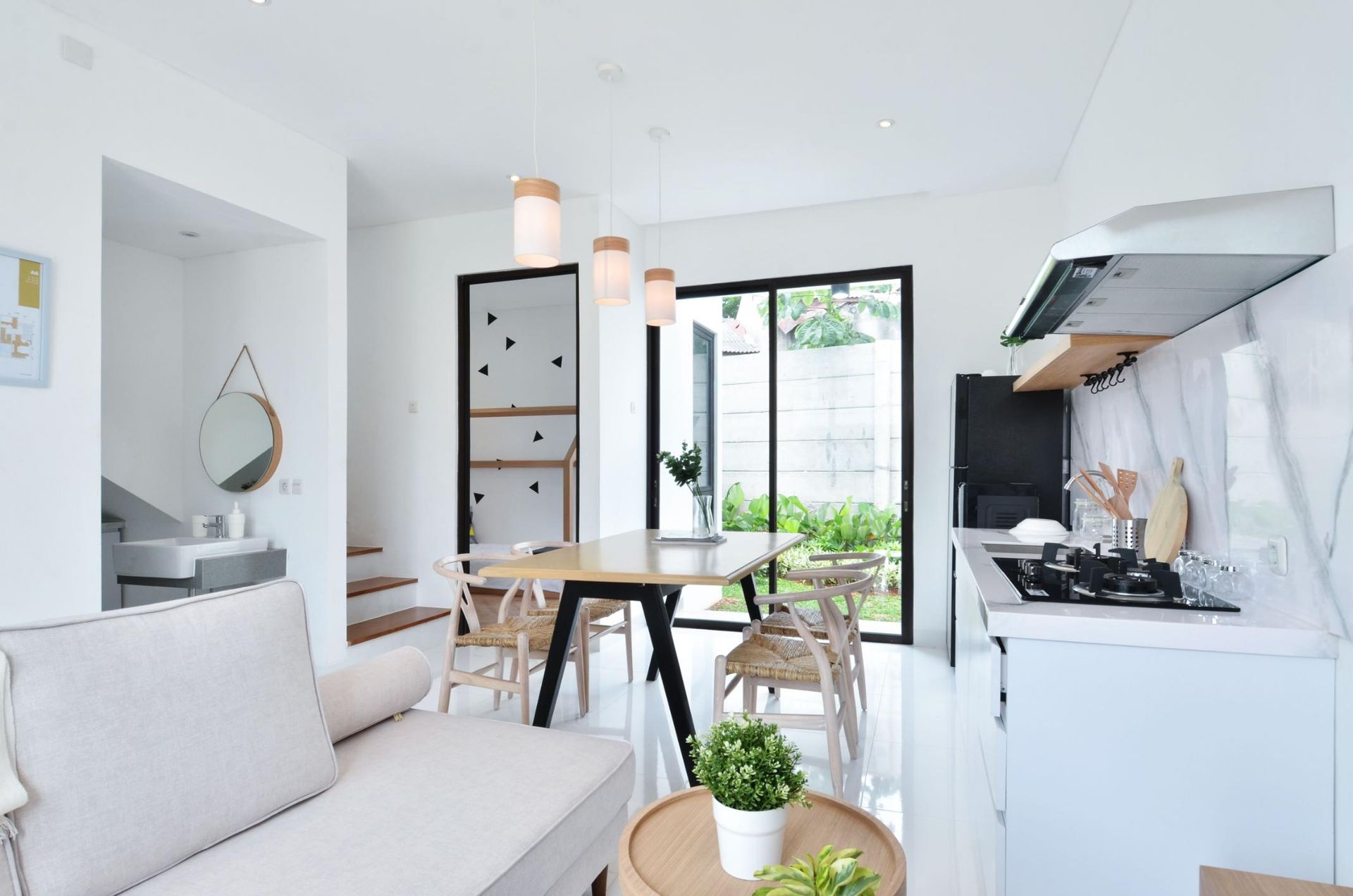 Bright modern kitchen-living area with white decor, dining table, open doors, and a small sofa