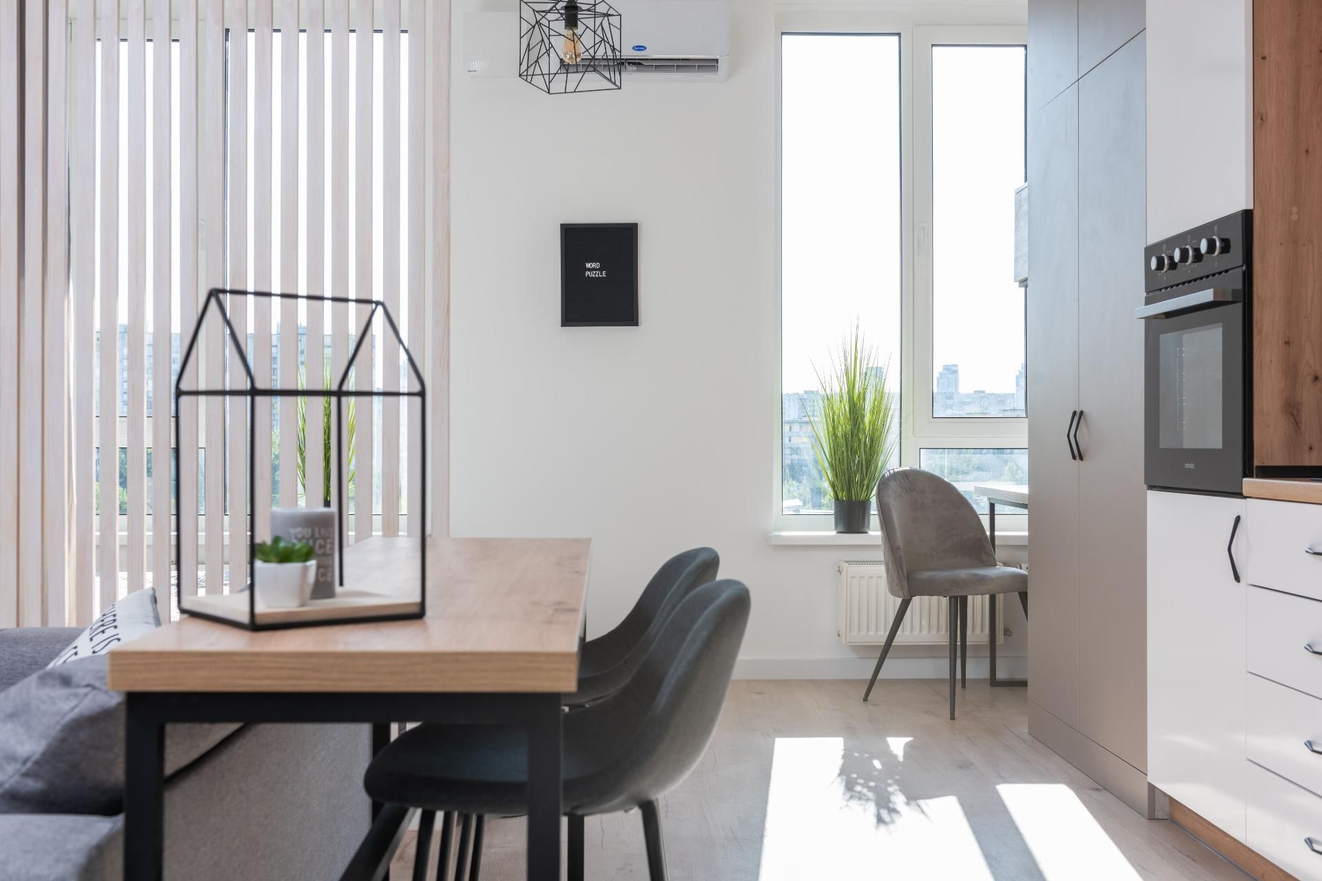 Modern kitchen and dining area with a large window, wooden table, and a glass terrarium centerpiece