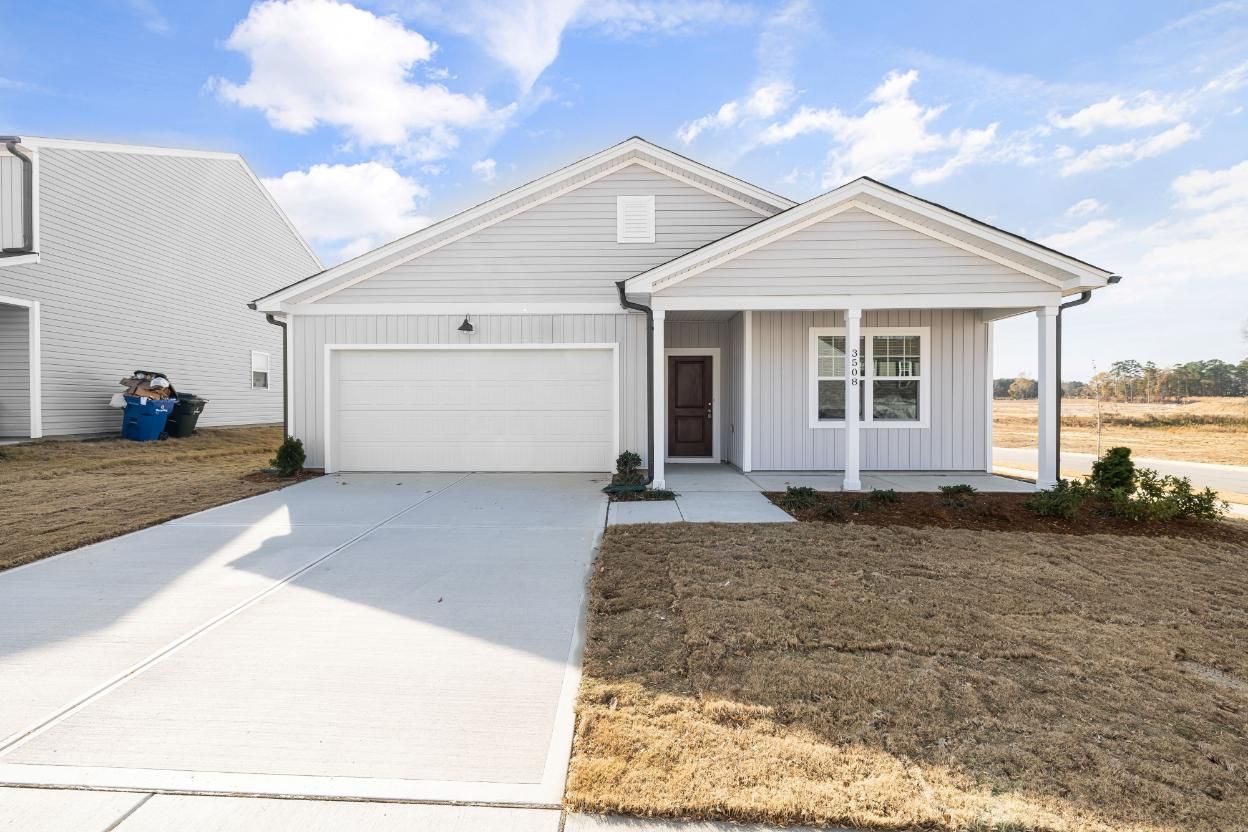 Single-story gray house with white trim, front garage, and a concrete driveway in a suburban neighborhood