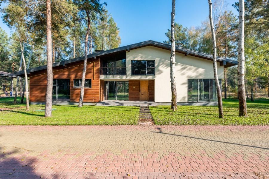 Modern house with large windows and wood siding in a wooded yard