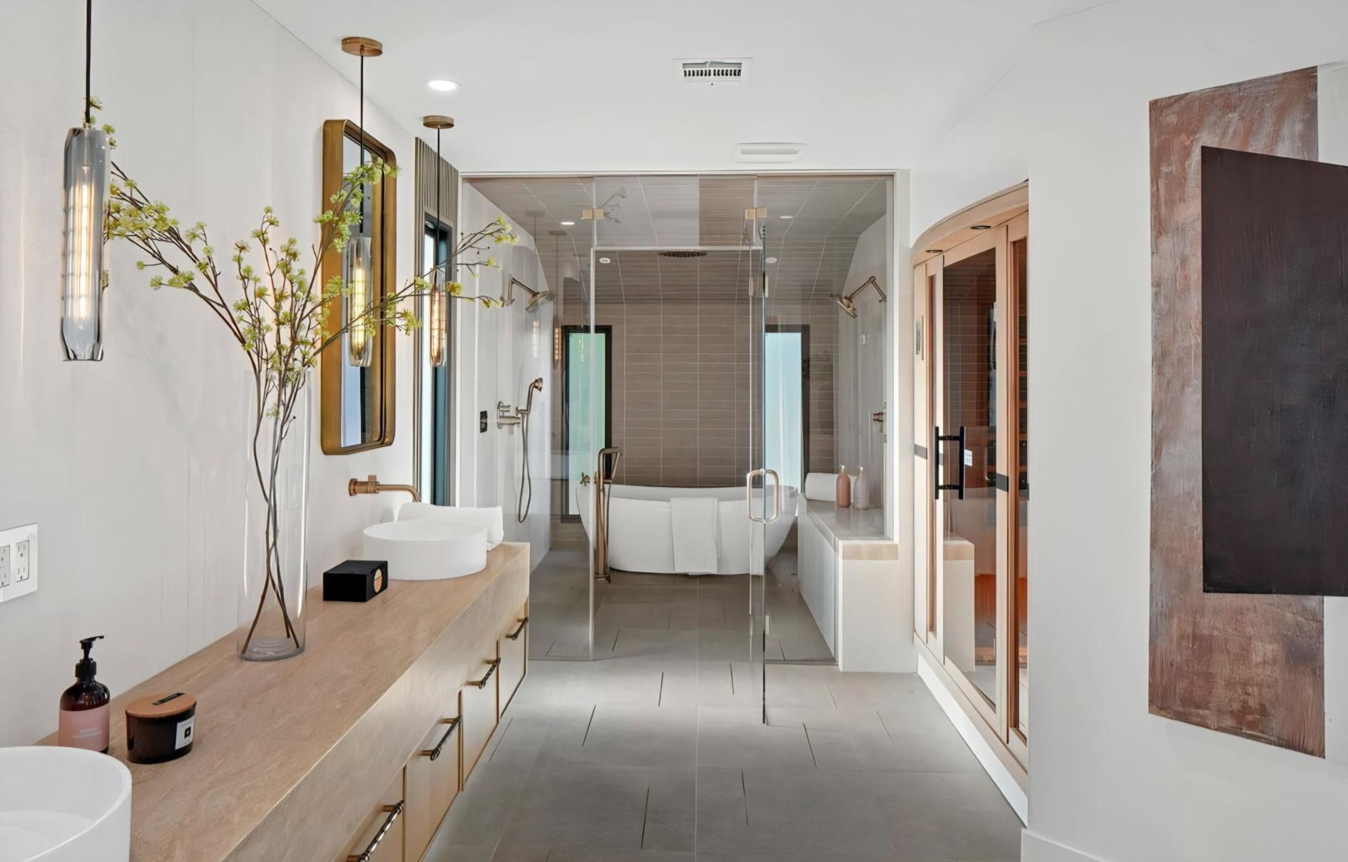 Bright, modern bathroom with a long vanity, mirrors, glass shower, and freestanding tub