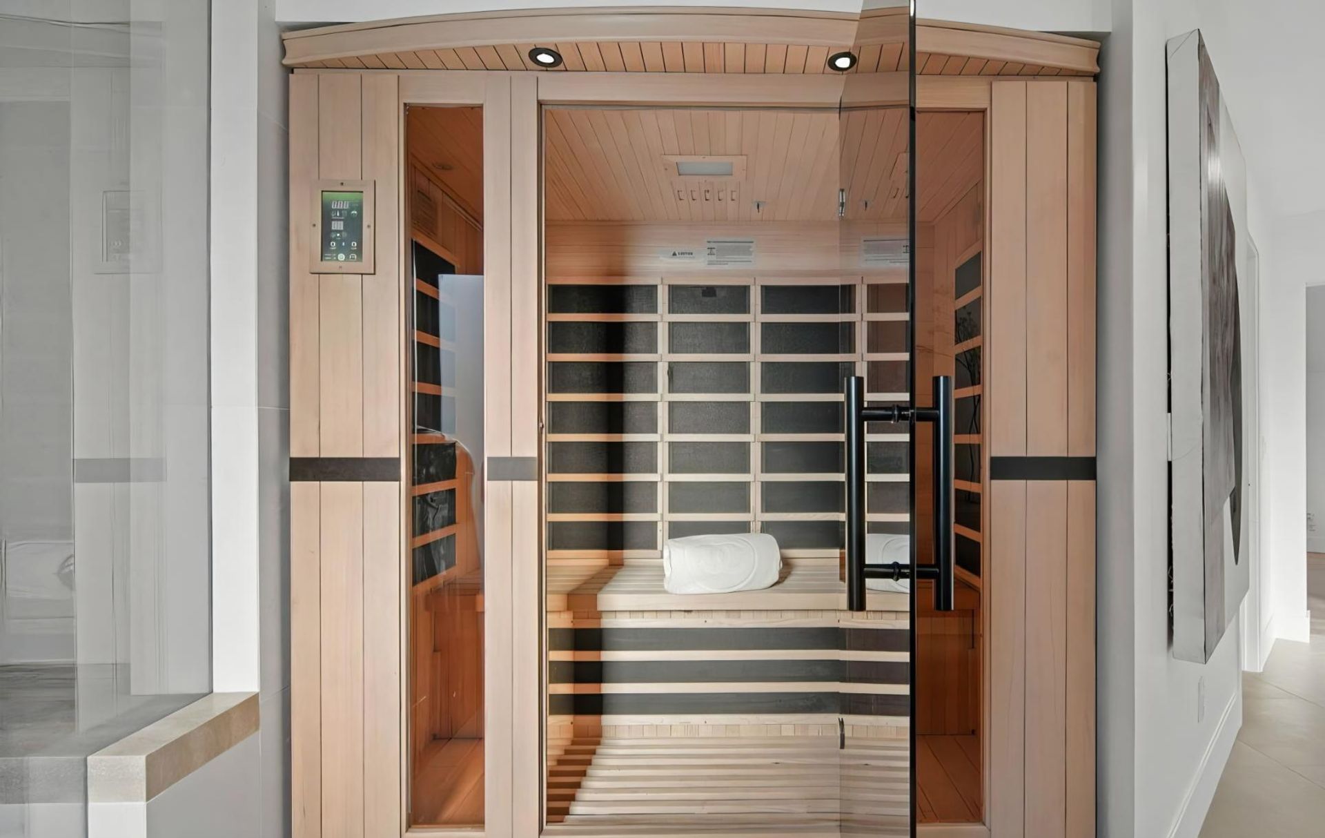 Wood-paneled sauna room with glass doors, benches, and a white towel inside