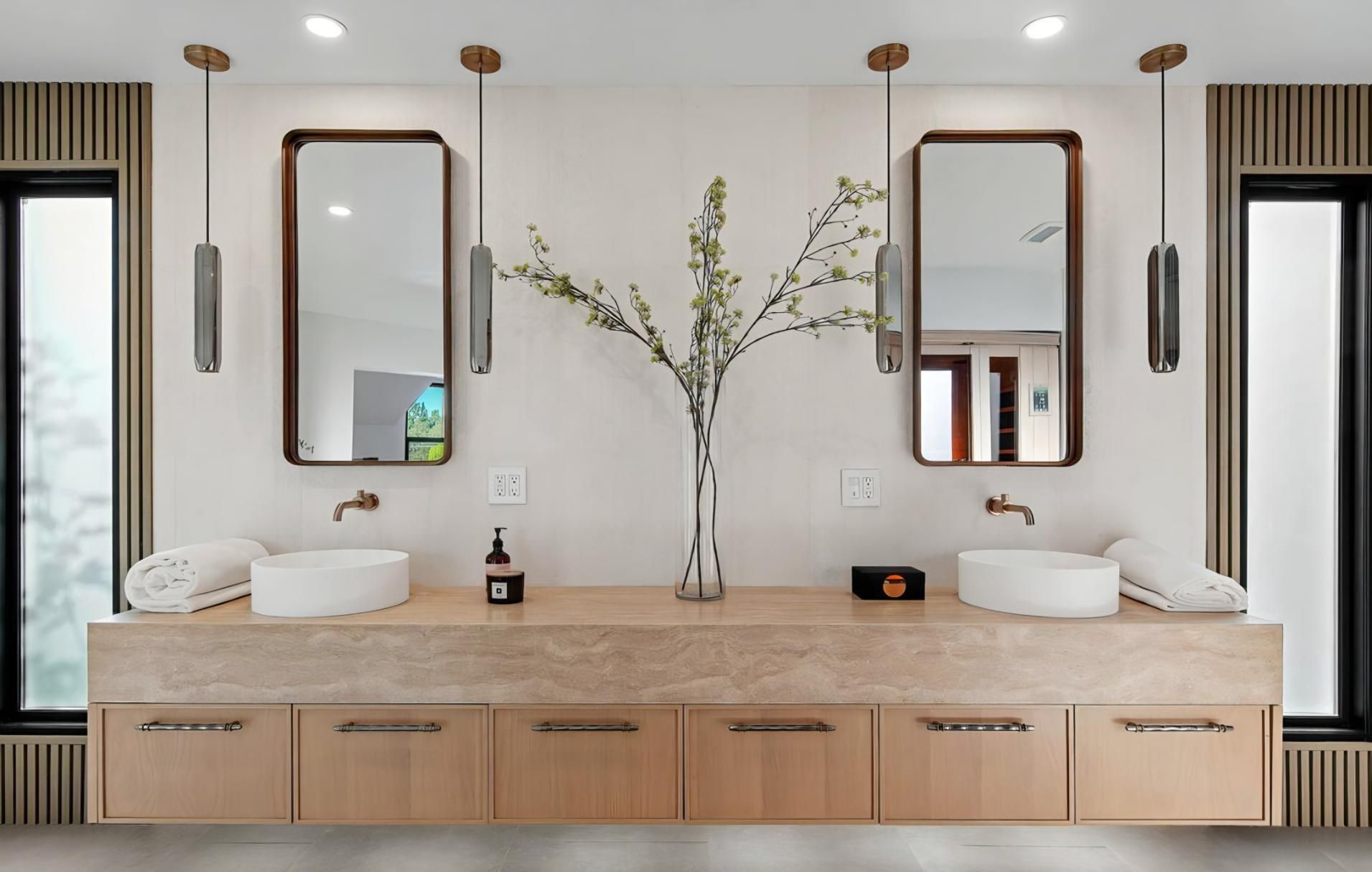 Modern double vanity bathroom with twin mirrors, vessel sinks, and light wood cabinets