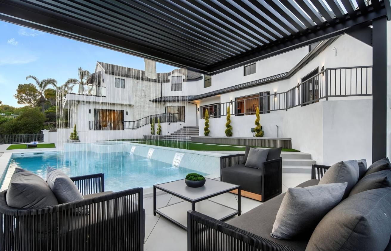 Modern backyard pool patio with black lounge seating and white contemporary house